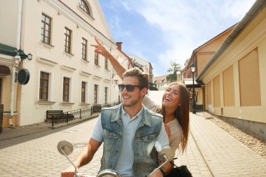 mutlu genç çift sürme scooter şehirde. Yakışıklı ve genç kadın seyahat. Macera ve tatil kavramı.