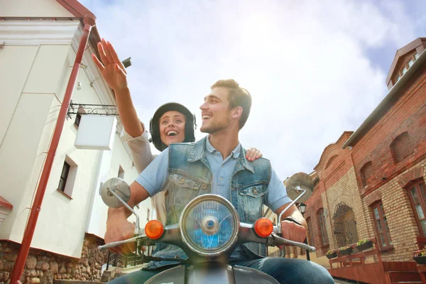 Feliz joven pareja montando scooter en la ciudad. Un chico guapo y una joven viajan. Concepto aventura y vacaciones . — Foto de Stock