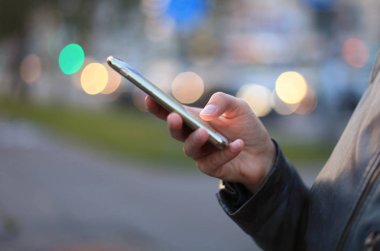 El holding modern smartphone ile boş ekran, closeup gece city adlı görüntülemek.