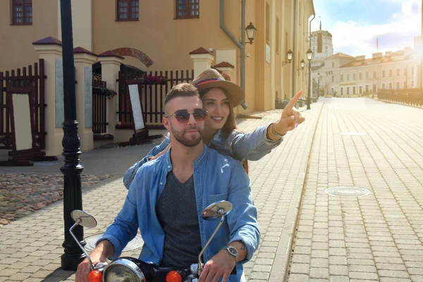 Feliz jovem casal montando scooter na cidade. Um tipo bonito e uma jovem viajam. Conceito de aventura e férias . — Fotografia de Stock