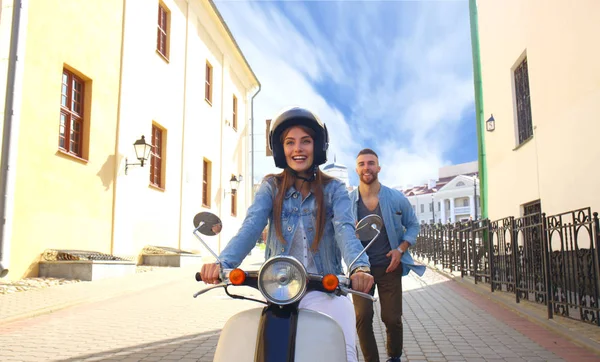 mutlu genç çift sürme scooter şehirde. Yakışıklı ve genç kadın seyahat. Macera ve tatil kavramı.
