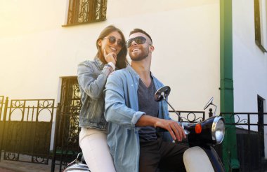 mutlu genç çift sürme scooter şehirde. Yakışıklı ve genç kadın seyahat. Macera ve tatil kavramı.