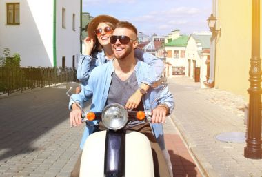 mutlu genç çift sürme scooter şehirde. Yakışıklı ve genç kadın seyahat. Macera ve tatil kavramı.