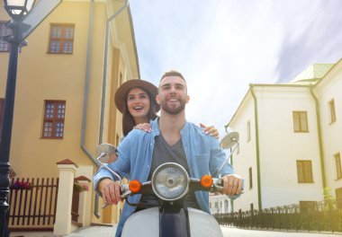 mutlu genç çift sürme scooter şehirde. Yakışıklı ve genç kadın seyahat. Macera ve tatil kavramı.