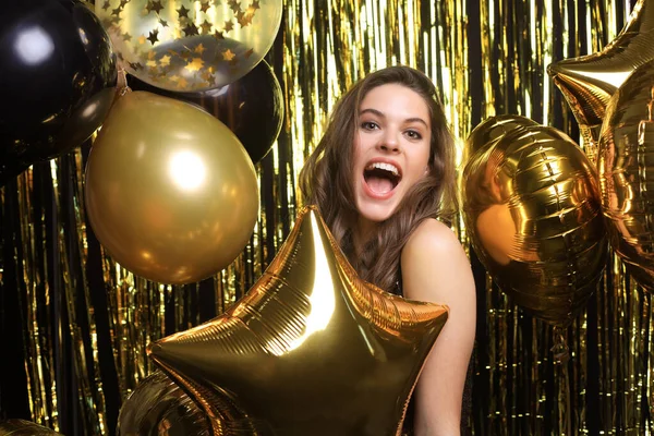 Glad kvinna i festliga kläder håller guld ballonger. — Stockfoto