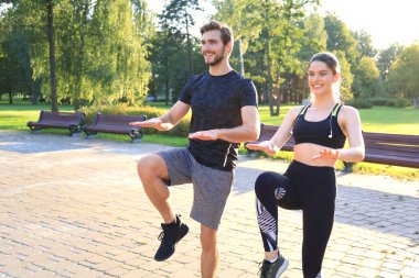 Genç çift parkta spor yaparken birlikte egzersiz yapıyor..