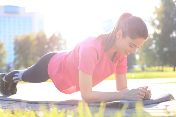 Apto jovem mulher fazendo prancha exercício ao ar livre no parque urbano . — Fotografia de Stock