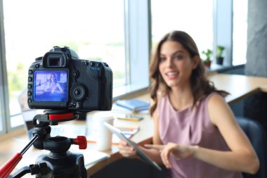 Güzel genç bir kadın blogu için yeni video çekerken konuşuyor ve gülümsüyor..