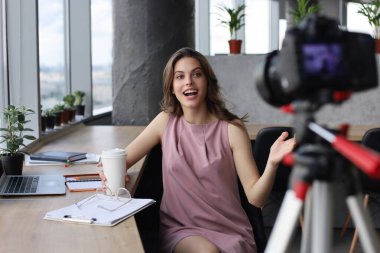 Güzel genç bir kadın blogu için yeni video çekerken konuşuyor ve gülümsüyor..