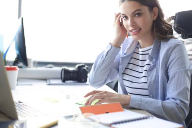Güzel iş kadını büro masasında otururken bir şeyler yazıyor.