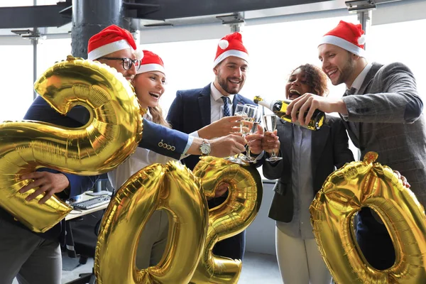 Gli uomini d'affari festeggiano le vacanze nel moderno ufficio bevendo champagne e divertendosi nel coworking. Buon Natale e Felice Anno Nuovo 2020 — Foto Stock