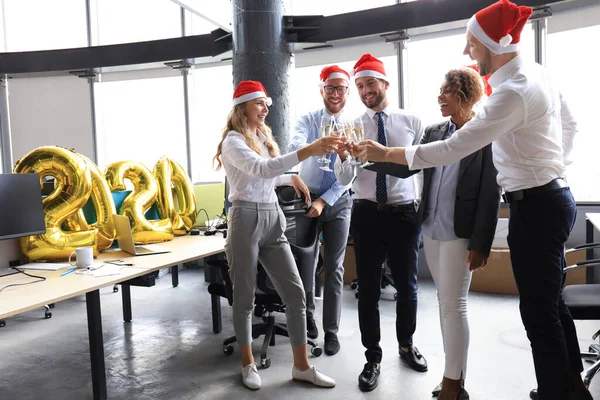 Business people are celebrating holiday in modern office drinking champagne and having fun in coworking. Merry Christmas and Happy New Year 2020