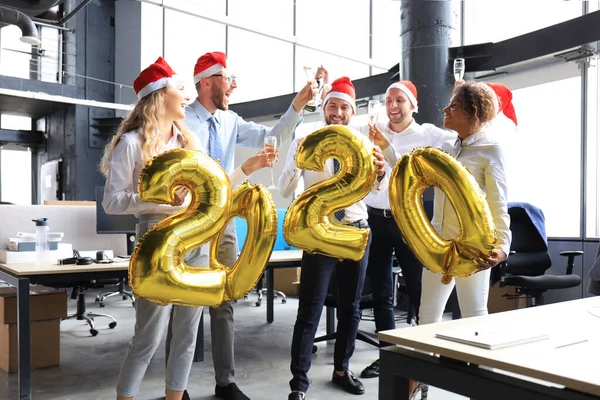 Ділові люди святкують свято в сучасному офісі питної шампанського і веселяться в коворкінгу. З новим роком та Різдвом Христовим 2020 — стокове фото