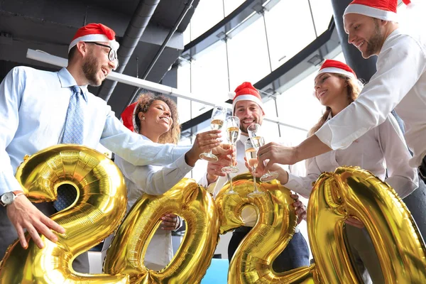 Gli uomini d'affari festeggiano le vacanze nel moderno ufficio bevendo champagne e divertendosi nel coworking. Buon Natale e Felice Anno Nuovo 2020 — Foto Stock