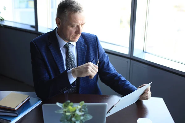 Fokuserad mogen affärsman djupt i tanken när du sitter vid ett bord i moderna kontor. — Stockfoto