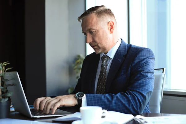 Fokuserad mogen affärsman djupt i tanken när du sitter vid ett bord i moderna kontor. — Stockfoto