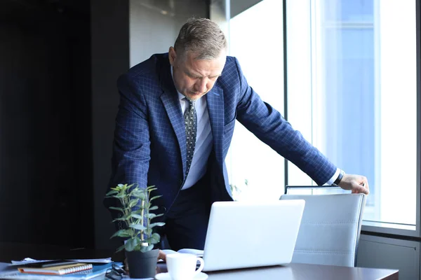 Элегантный зрелый бизнесмен анализирует данные во время работы в офисе . — стоковое фото
