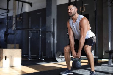 Fit ve kaslı adam bir spor salonunda bir egzersiz sınıfı sırasında bir dambıl kaldırma odaklanmış.