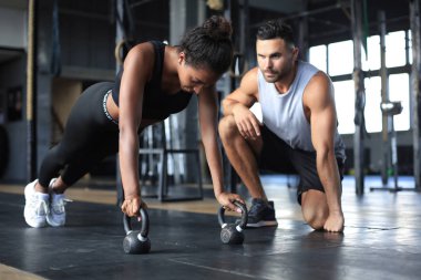 Sportif bir kadın spor salonunda şınav çekiyor, erkek arkadaşı onu izliyor..