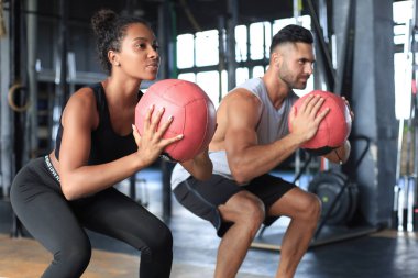 Güzel genç spor çifti jimnastik salonunda sağlık topuyla antrenman yapıyor..
