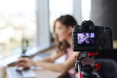 Güzel genç bir kadın blogu için yeni video çekerken konuşuyor ve gülümsüyor..