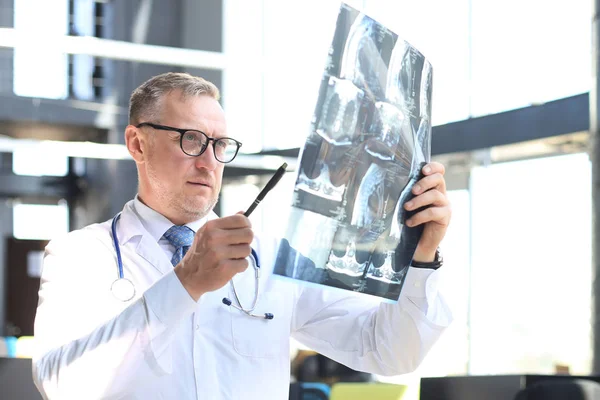 Dokter therapeut kijkt goed naar de röntgenfoto. — Stockfoto