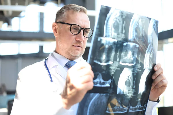 Dokter therapeut kijkt goed naar de röntgenfoto. — Stockfoto