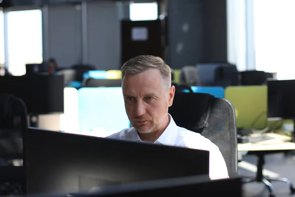 Reifer Geschäftsmann arbeitet im modernen Büro am Computer. — Stockfoto