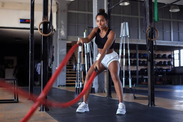 Passform kvinna med hjälp av stridsrep under styrketräning på gymmet. — Stockfoto