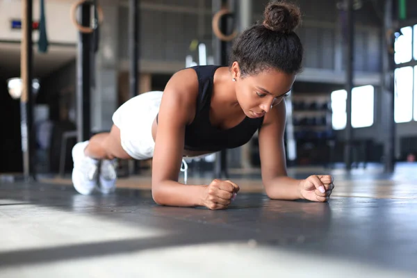 Retrato de uma mulher muscular em uma posição de prancha. — Fotografia de Stock