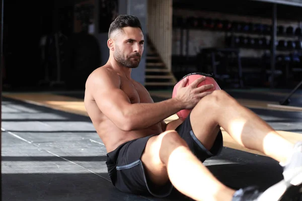 Fit y el hombre musculoso haciendo ejercicio con balón de medicina en el gimnasio . — Foto de Stock