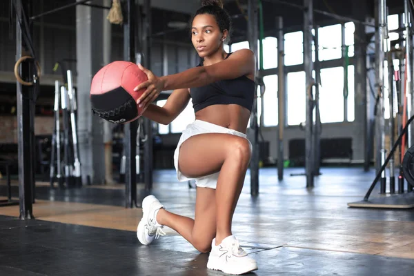 Donna in forma e muscolosa che si allena con la palla medica in palestra. — Foto Stock