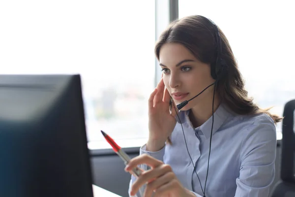 Hermosa sonriente trabajador del centro de llamadas en los auriculares está trabajando en la oficina moderna —  Fotos de Stock