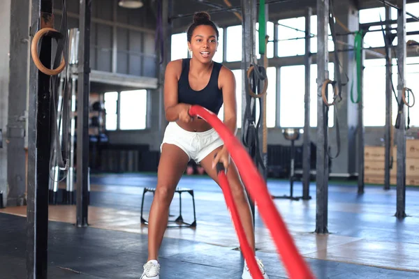 Fit mulher usando cordas de batalha durante o treinamento de força no ginásio. — Fotografia de Stock