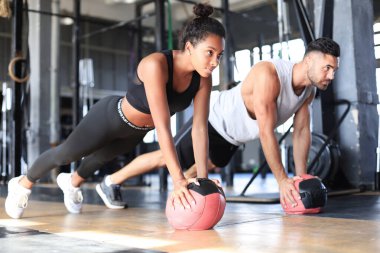 Güzel genç spor çifti jimnastik salonunda sağlık topuyla antrenman yapıyor..