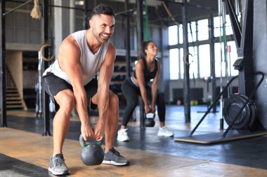 Formda ve kaslı bir çift spor salonunda egzersiz yaparken dambıl kaldırmaya odaklanmış..