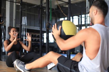 Formda ve kaslı bir çift spor salonunda ilaç topuyla egzersiz yapıyor..