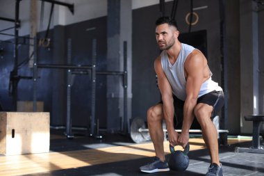 Fit ve kaslı adam bir spor salonunda bir egzersiz sınıfı sırasında bir dambıl kaldırma odaklanmış.