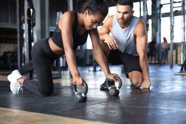 Sportif bir kadın spor salonunda şınav çekiyor, erkek arkadaşı onu izliyor..
