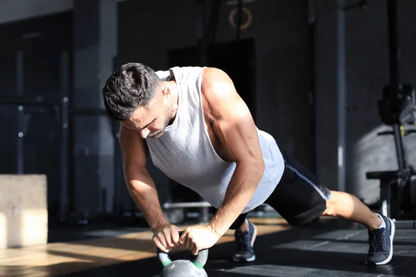 Fit і м'язистий чоловік зосереджений на підйомі гантелі під час занять фізичними вправами в спортзалі . — стокове фото