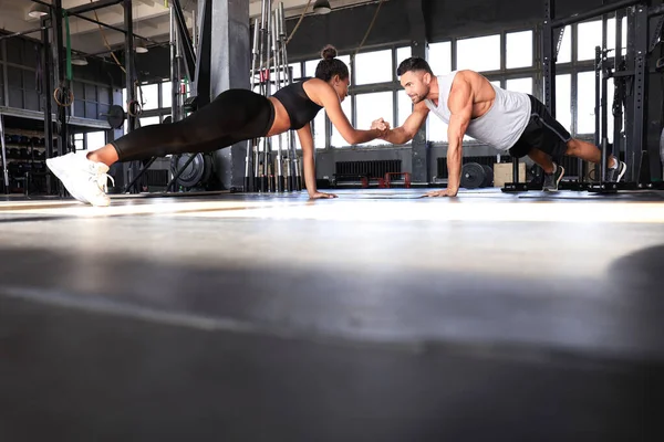 Pareja deportiva haciendo ejercicio de tablón en el gimnasio . — Foto de Stock