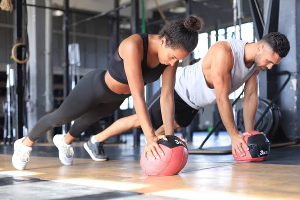 Hermosa pareja de jóvenes deportes está trabajando con la pelota de la medicina en el gimnasio. — Foto de Stock