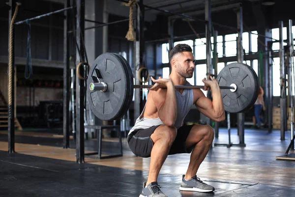 Hombre musculoso haciendo ejercicio en el gimnasio haciendo ejercicios con barra en el bíceps . —  Fotos de Stock