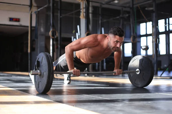 Fit i muskularny mężczyzna robi poziome pompki ze sztangą w siłowni. — Zdjęcie stockowe