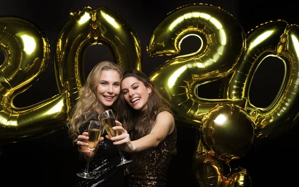 Duas jovens a beber champanhe. Imagem de meninas com balões isolados em fundo preto . — Fotografia de Stock