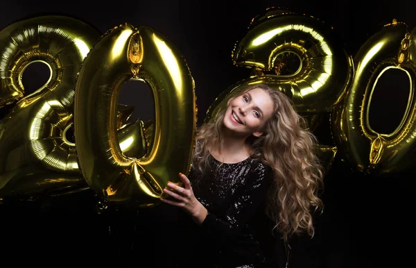 Happy gorgeous girl in stylish sexy party dress holding gold 2020 balloons, having fun at New Year 's Eve Party . — стоковое фото