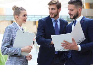 Ofis toplantısında iş görüşmesi ne zaman ayakta duran üç genç işadamı.