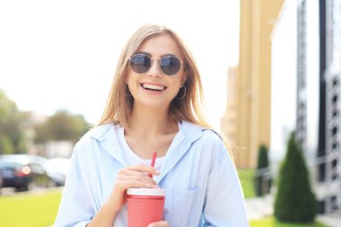 Havalı hippi kız şehir arka planında kokteyl içiyor..