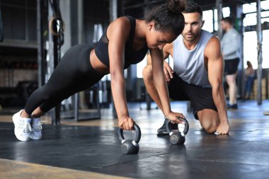 Sportif bir kadın spor salonunda şınav çekiyor, erkek arkadaşı onu izliyor..