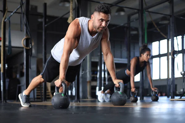 Sporty man and woman doing push-up in a gym. — Stock Photo, Image